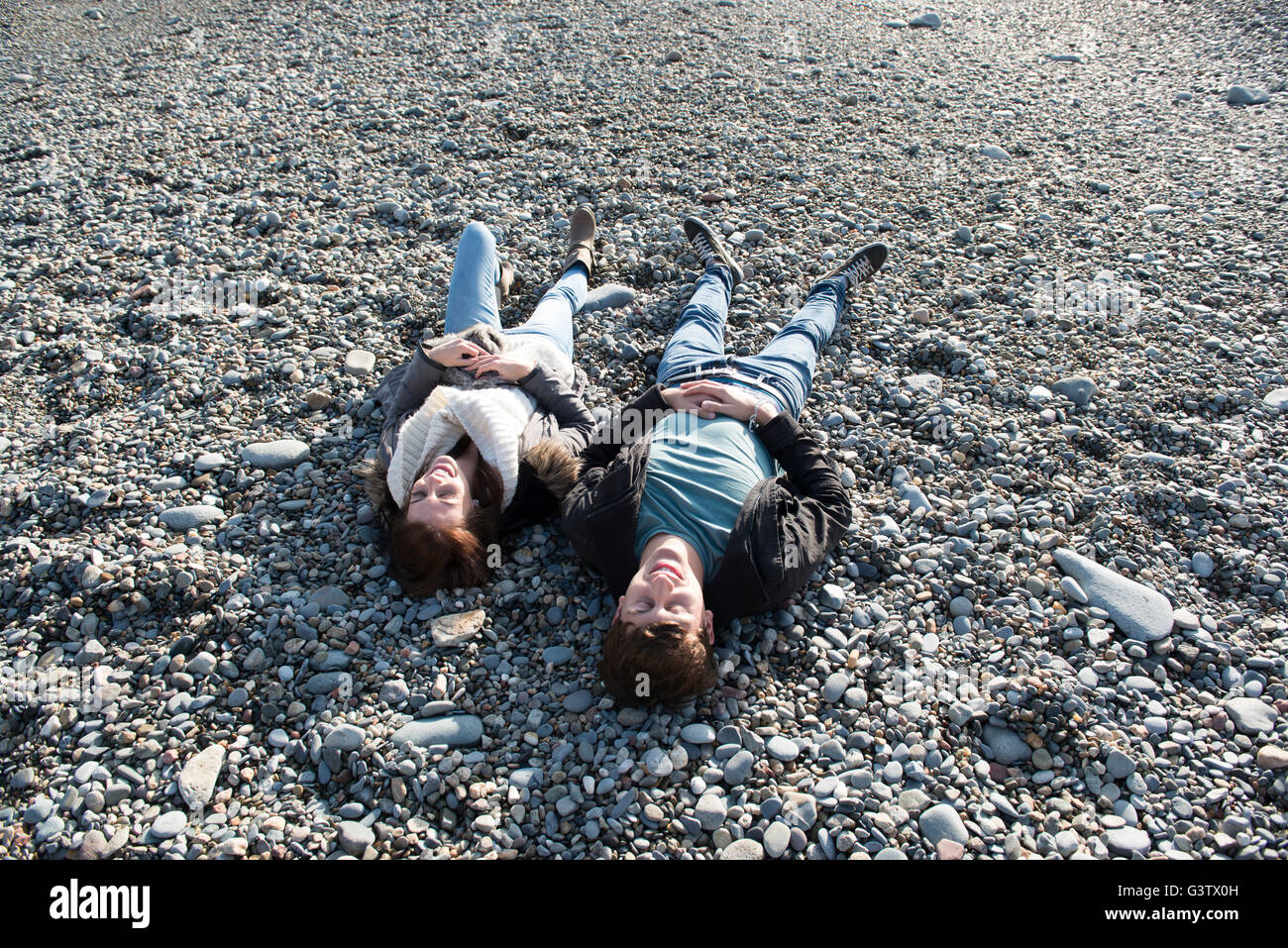 A young couple laying together on the beach at Porthmadog. Stock Photo