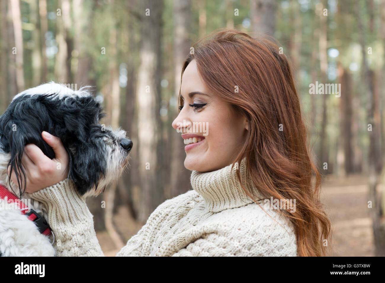 A young woman stroking a dog on a forest walk in Autumn. Stock Photo