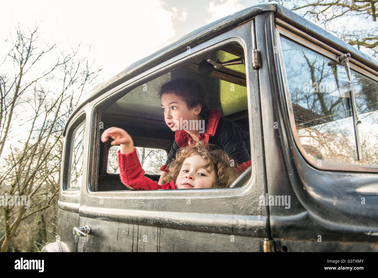 Two young children playing in a vintage car. Stock Photo