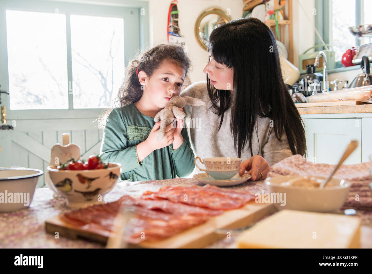 A six year old girl being comforted by her mother at the dinner table. Stock Photo