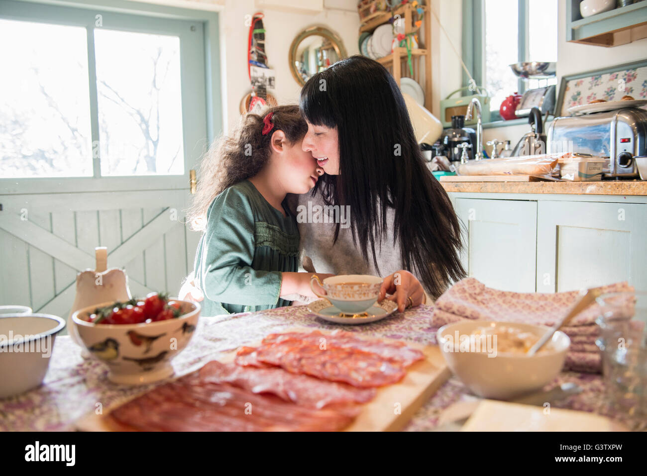 A six year old girl being comforted by her mother at the dinner table. Stock Photo