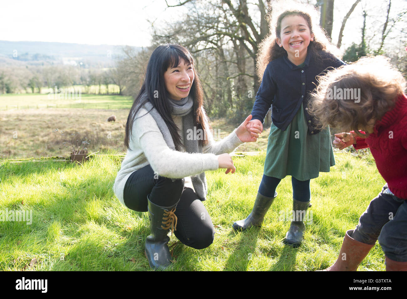 A mother and her two children enjoying being out in the garden on an early Spring day. Stock Photo