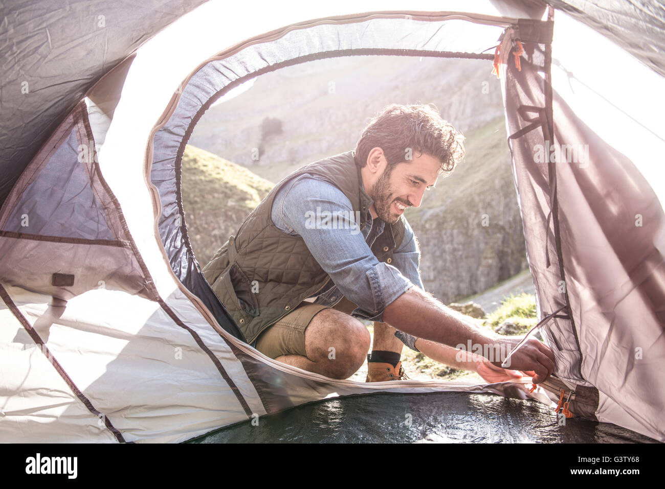 A mountaineer pitching his tent in rugged terrain Stock Photo Alamy
