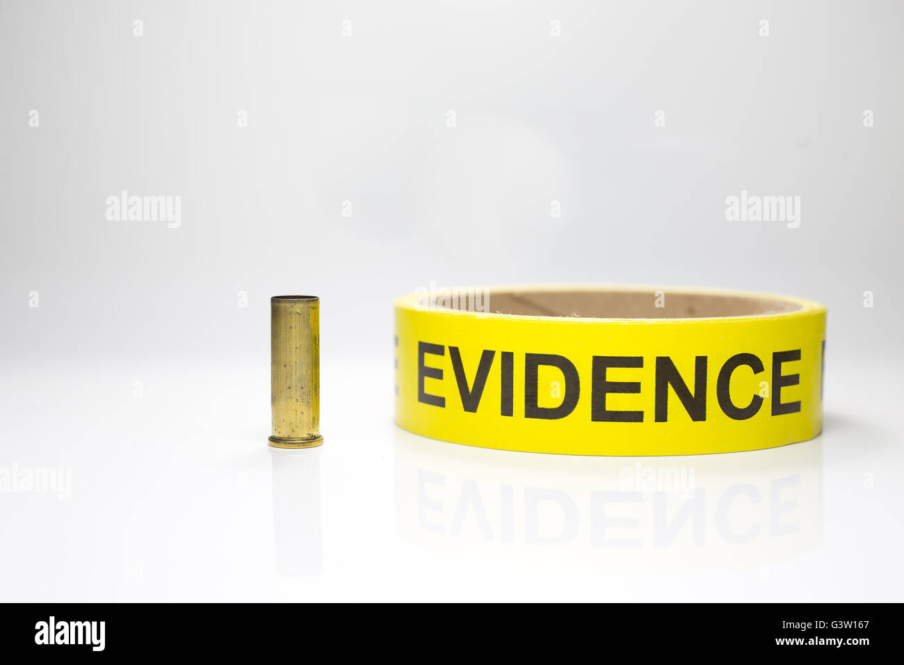 evidence tape with brass bullet case on white background Stock Photo