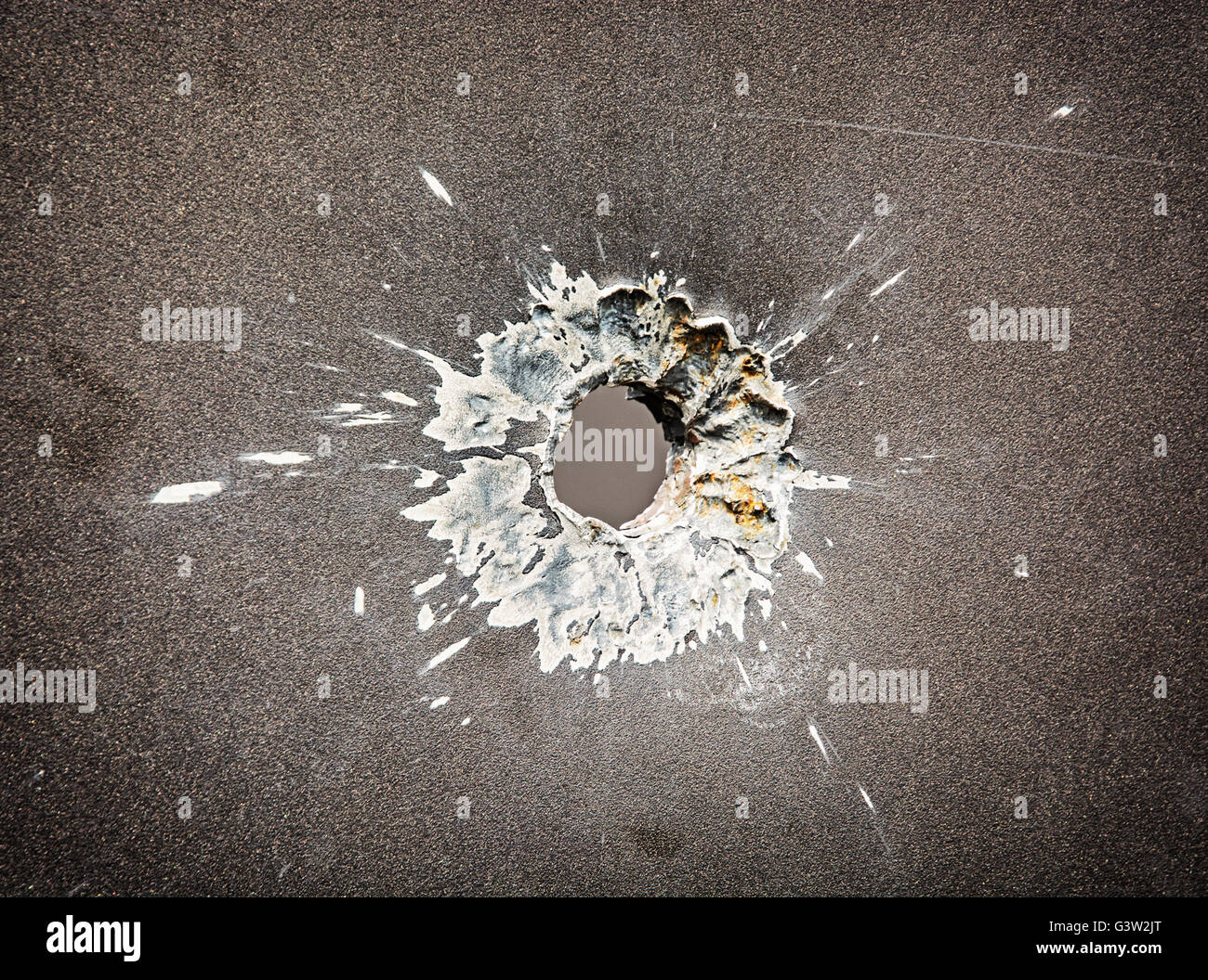 Bullet hole in the metal plate. Weapons theme. Armed conflict. Symbolic object. Detail of shot. Stock Photo
