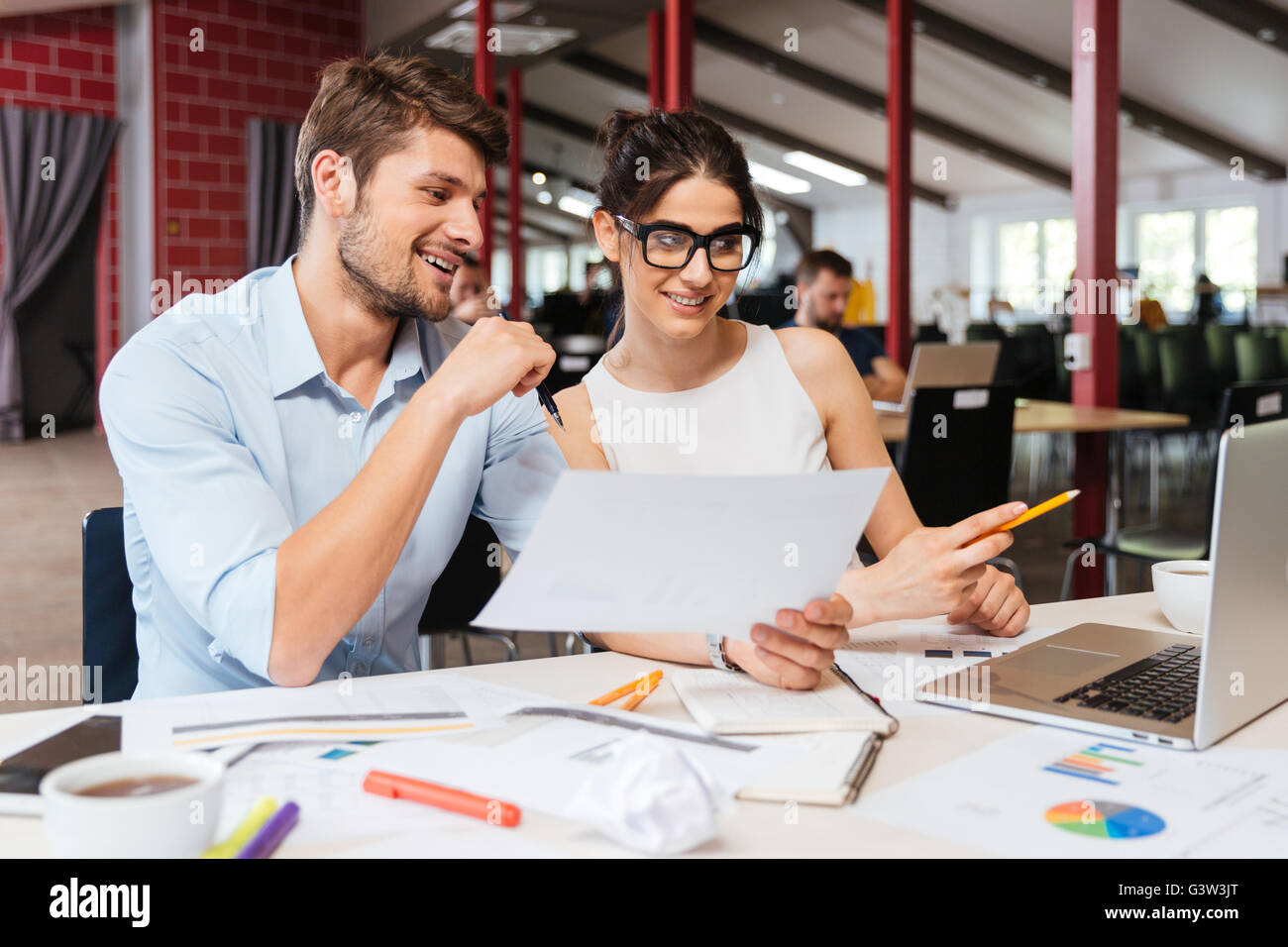 Happy young business man and woman sitting and working together in ...