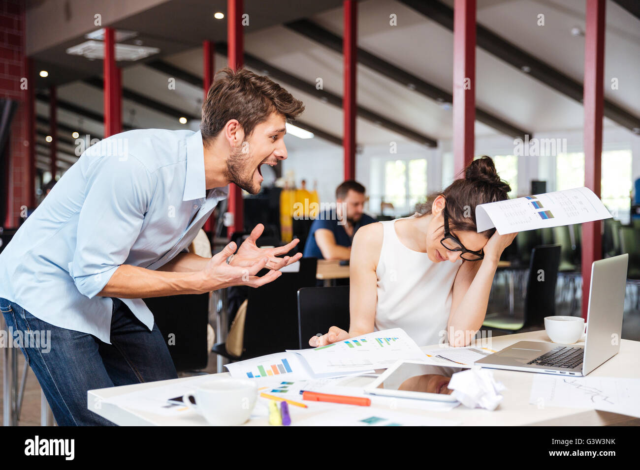 Mad crazy young businessman arguing with sad stressed businesswoman at work in office Stock Photo