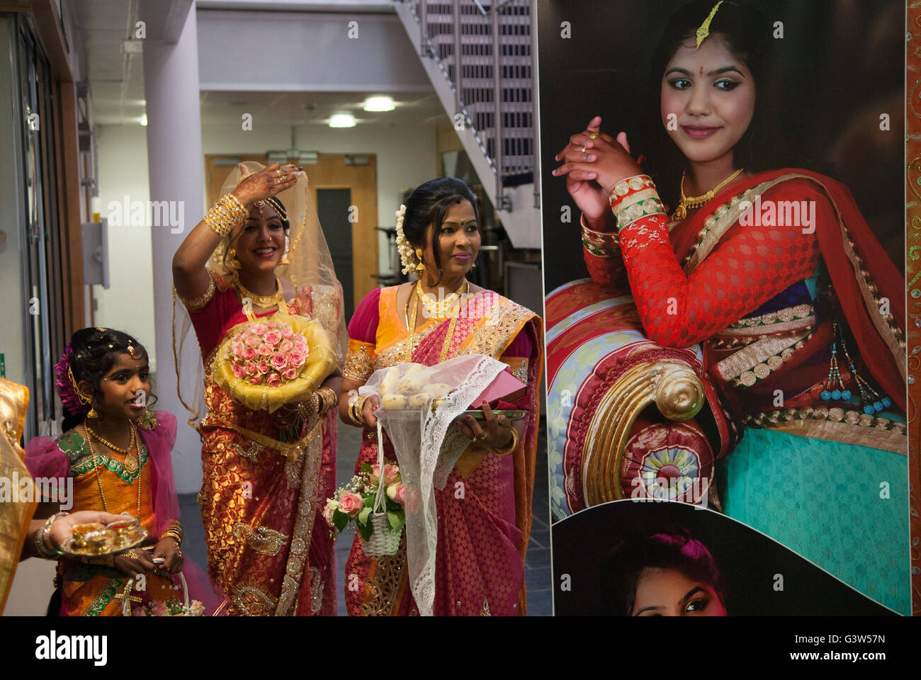 Hindu UK Coming of Age celebration party London. The display photograph is of the young woman. She is on the left (hand raised) her mother to her right.  She is 16yrs old. Mitcham south London England. They  are welcoming guests to the very big Ritushuddhi,  also called as Ritu Kala Samskara party. England. A celebration and the transition to womanhood.   2010s 2016 UK  HOMER SYKES Stock Photo