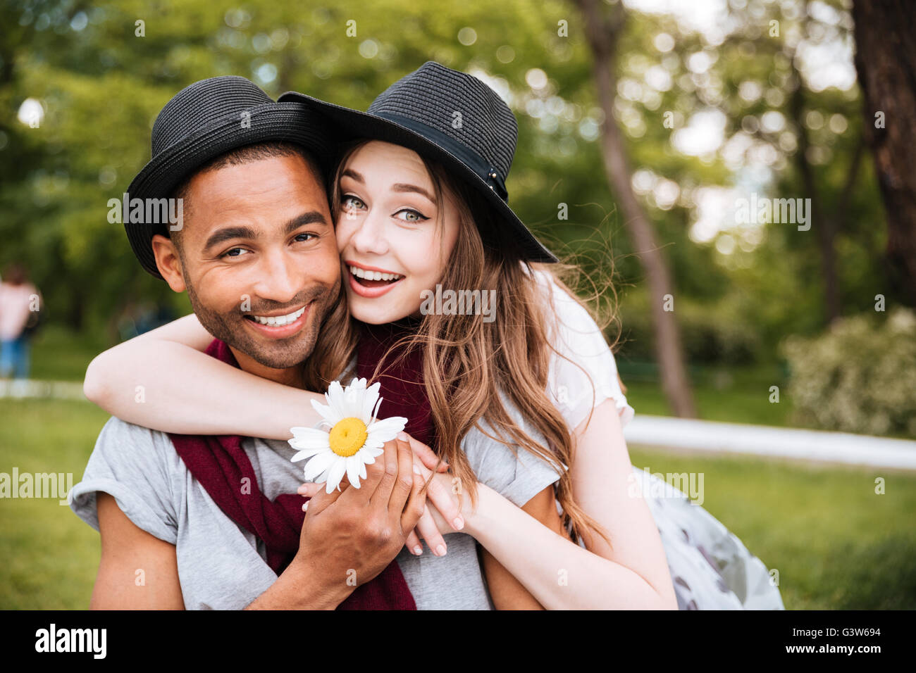 Portrait of cheerful young couple hugging and smiling in park Stock ...