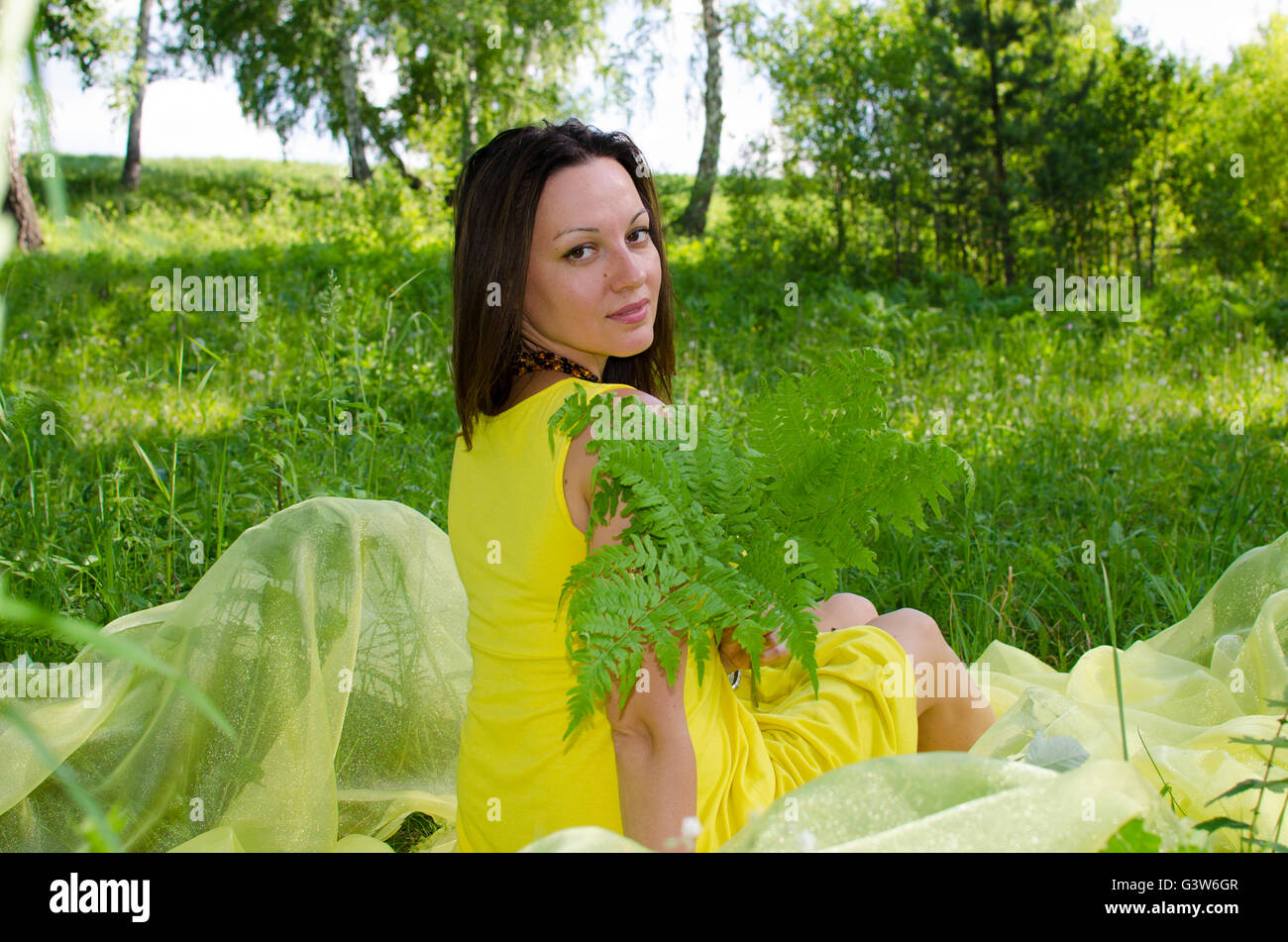 The girl sits on a grass in the summer wood has a rest, the girl, the ...
