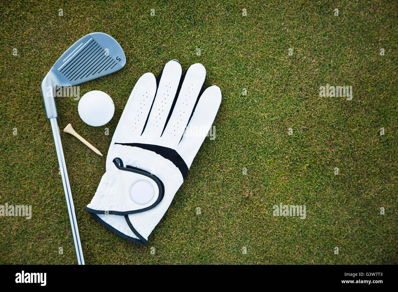 Golf glove, club, ball and tee on golf course Stock Photo