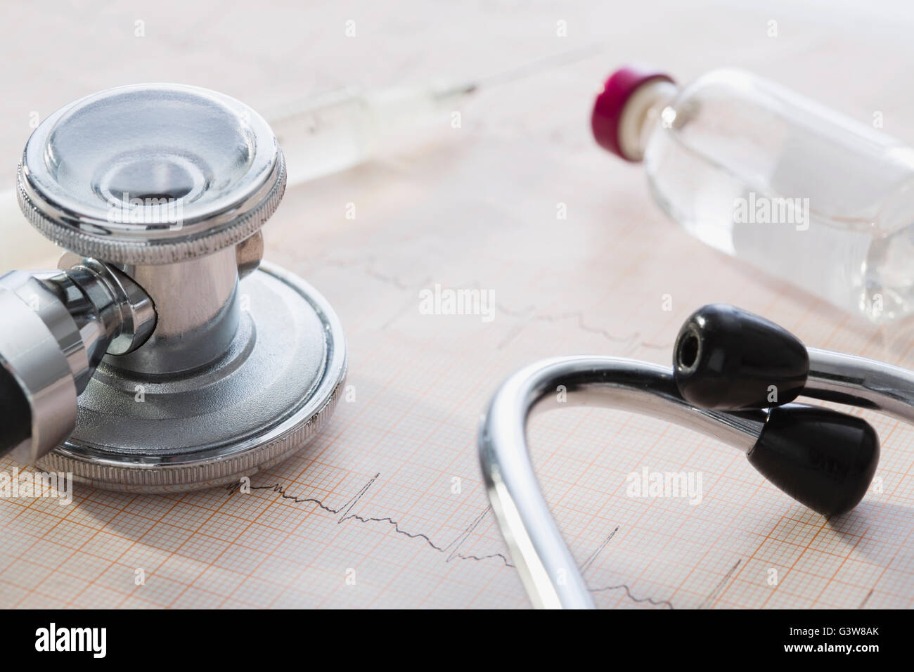 Stethoscope and syringe  lying on EKG results Stock Photo