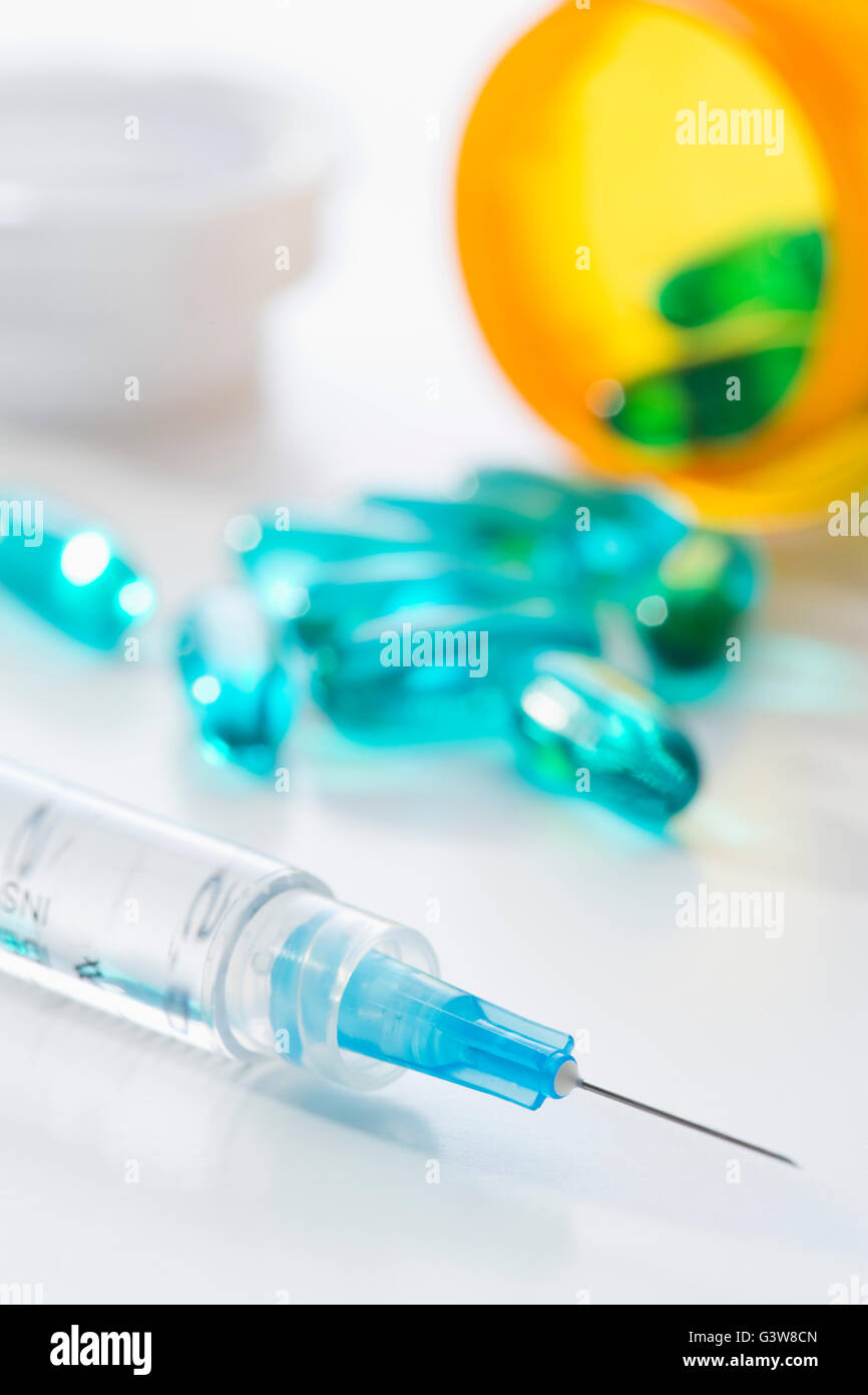 Syringe and blue capsules Stock Photo