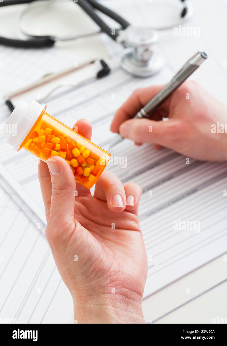 Doctor holding pill bottle and filling documents Stock Photo