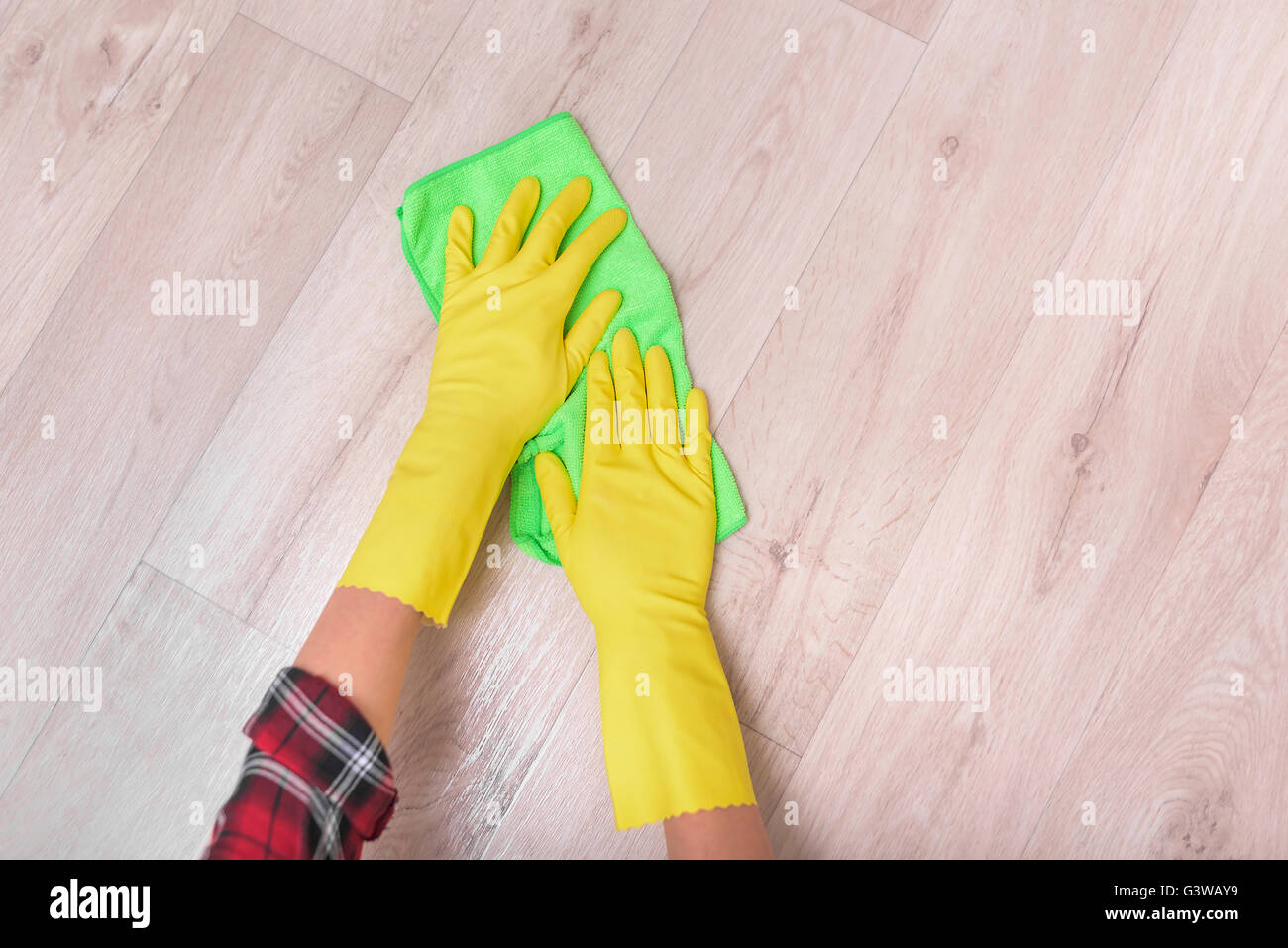 Female hands in yellow gloves wipe the floor rag. Stock Photo