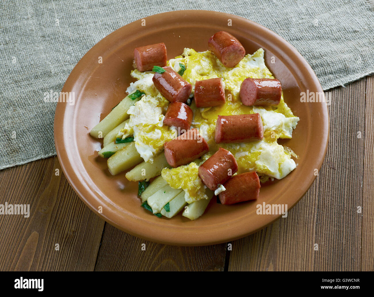 Huevos rotos con chistorra.scrambled eggs with sausage and potatoes. Mexican style. Stock Photo