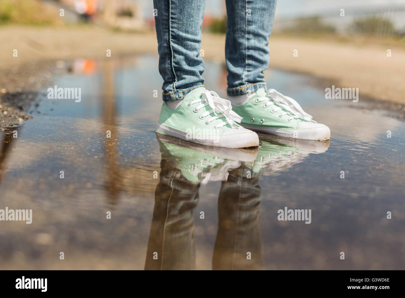 Woman in sport shoes standing in a puddle. Close up shot of foots in a water Stock Photo