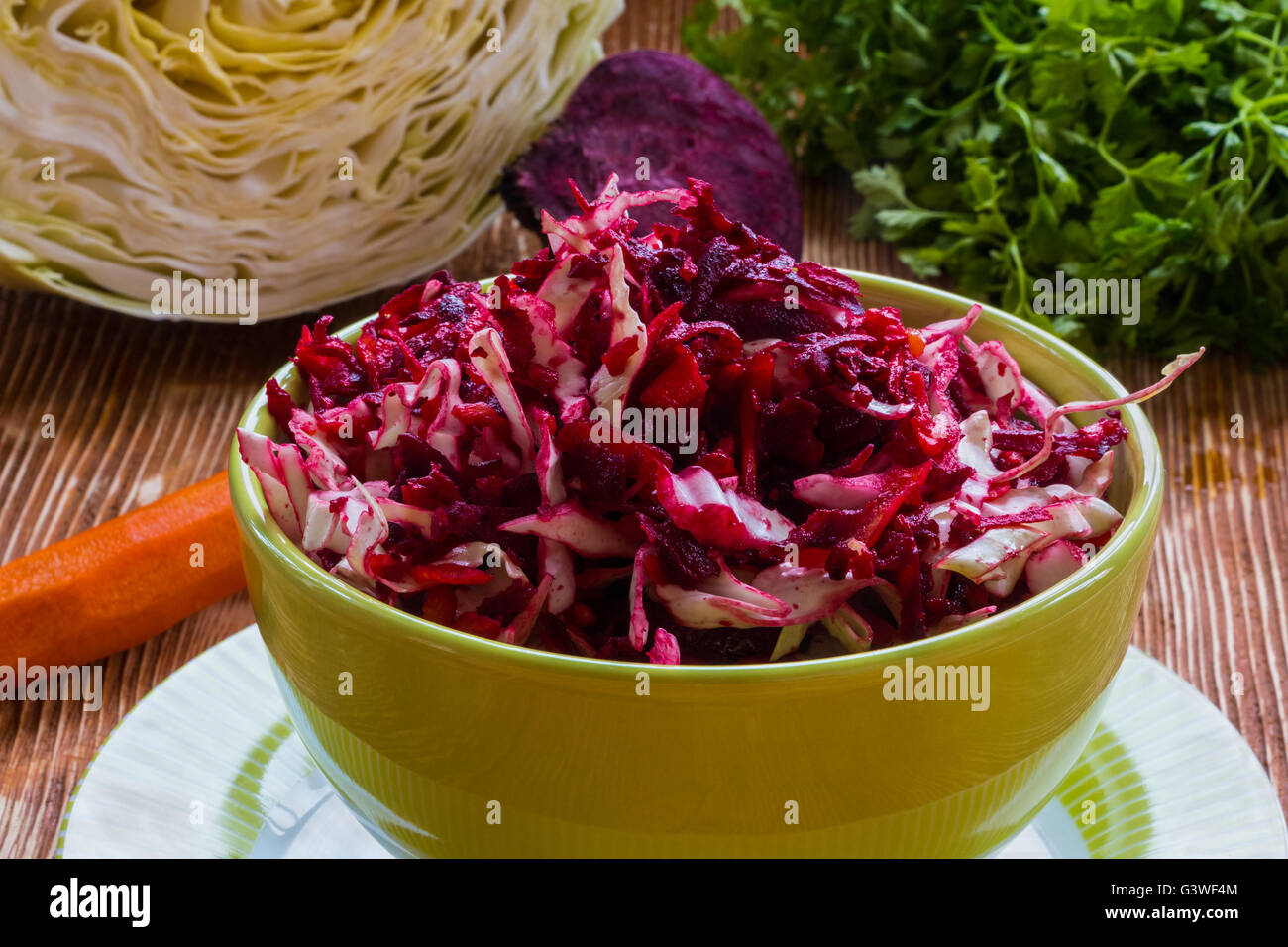 Diet salad with beetroot, carrot, cabbage, olive oil and lemon. Served in a bowl on wooden background. Stock Photo