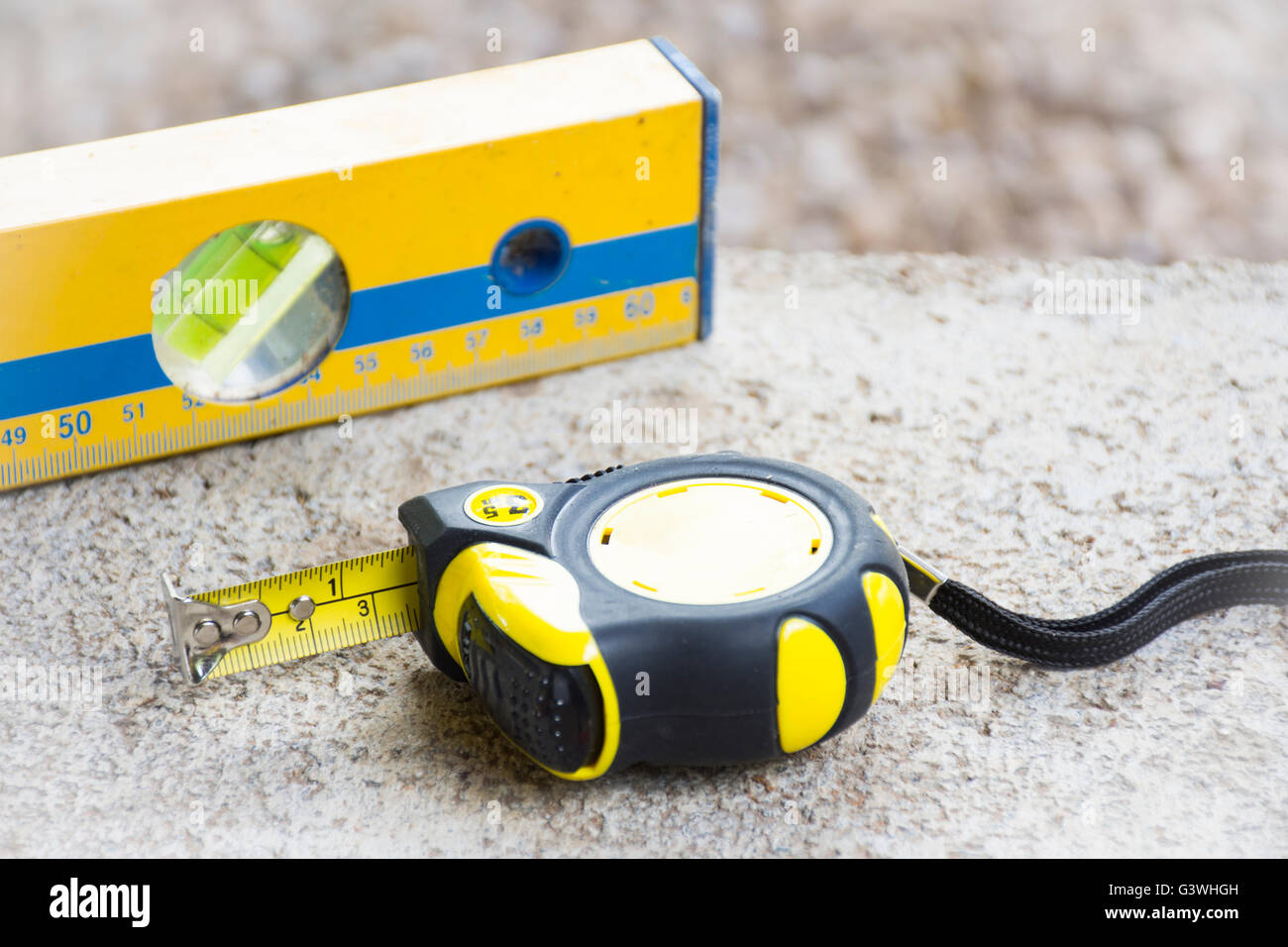 Tape measure and used level tool on brick with background rock nature