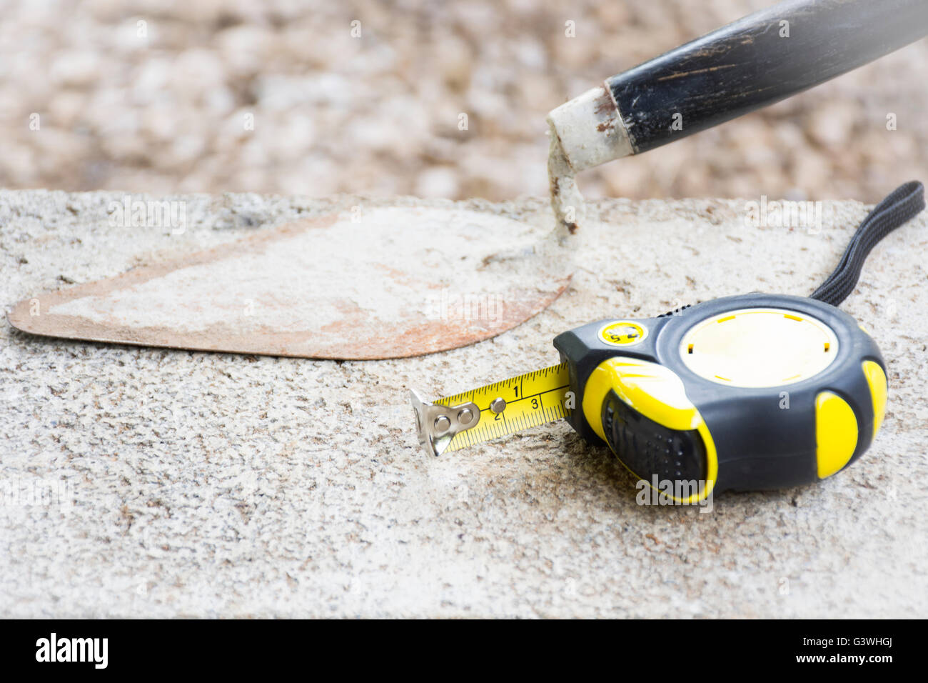 Tape measure and used trowel tool on brick with background rock nature