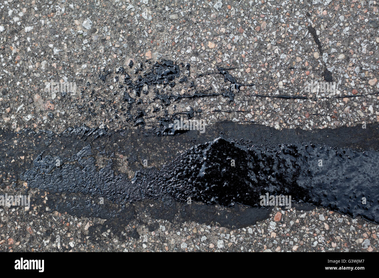 Strip of fresh tar on a weathered asphalt surface. Stock Photo