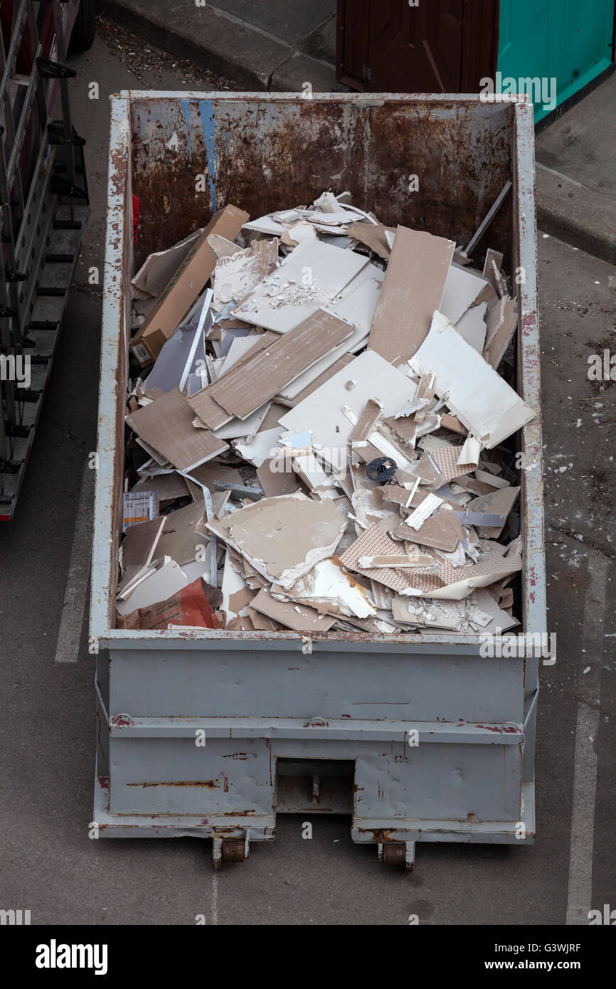 A roll-off dumpster filled with pieces of drywall and other construction debris. Stock Photo