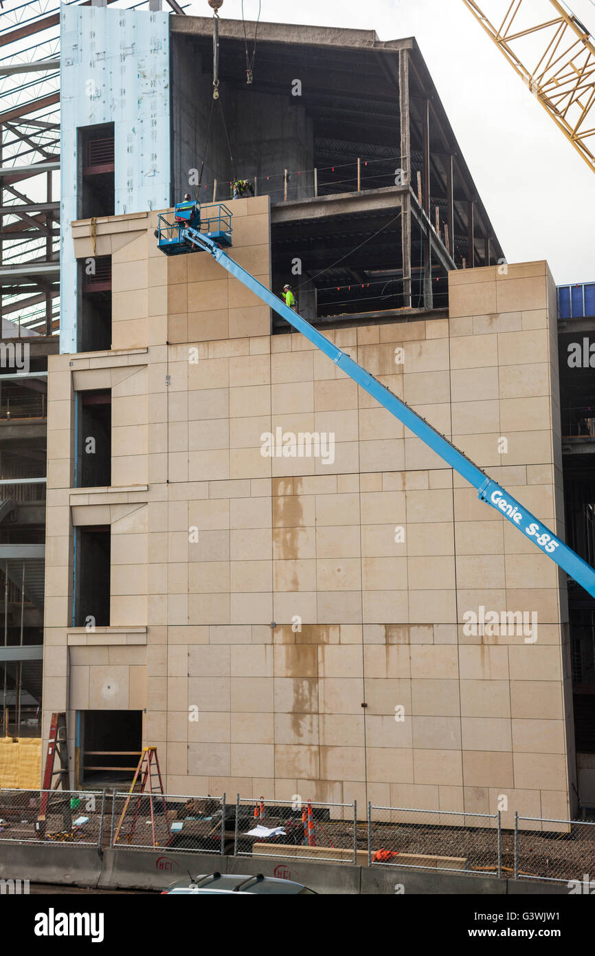 People work on the façade of a building under construction. Stock Photo