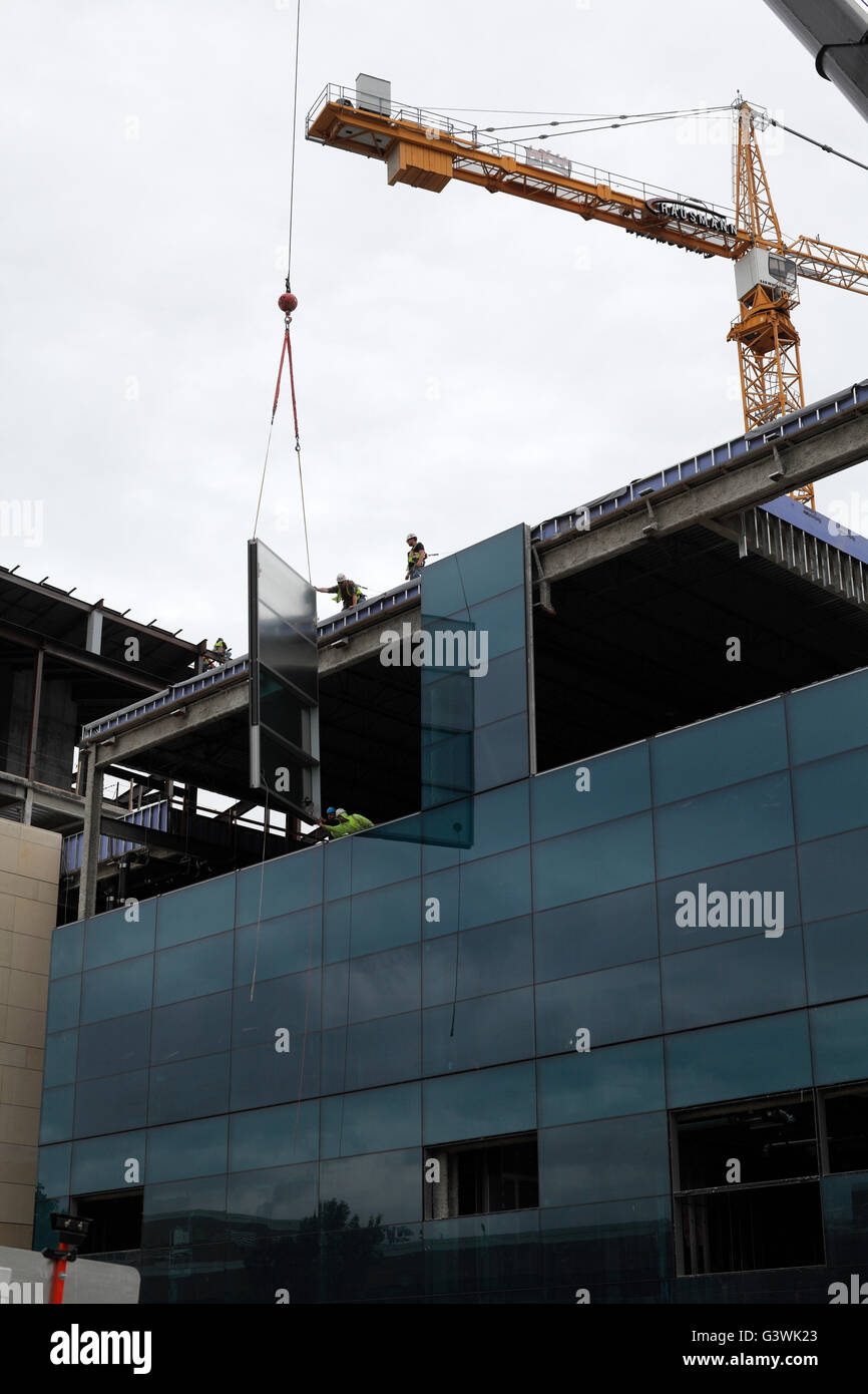 Building crew prepares to mount window to side of building using a crane. Stock Photo