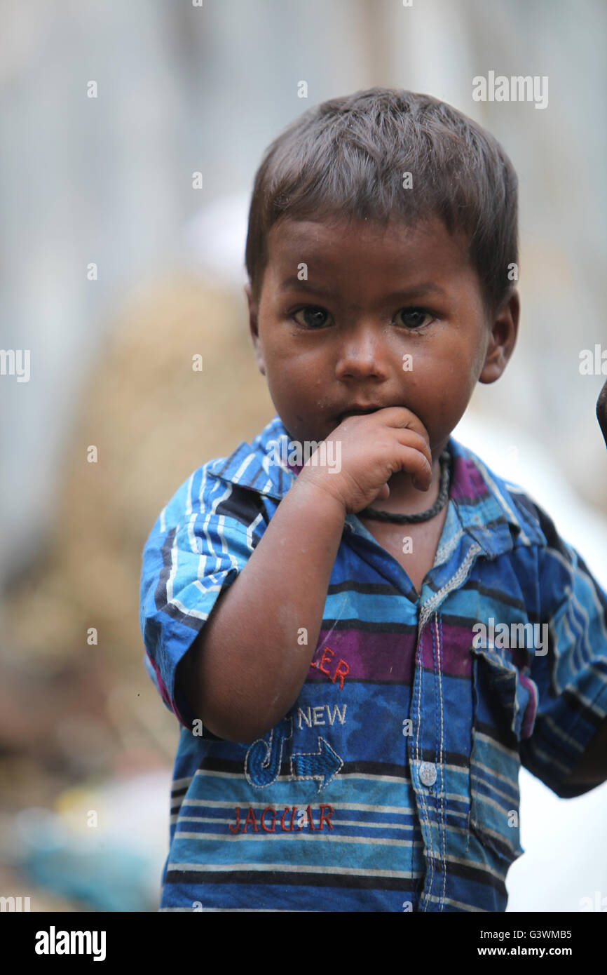 A portrait of a poor little Indian boy putting finger in his mouth. Stock Photo