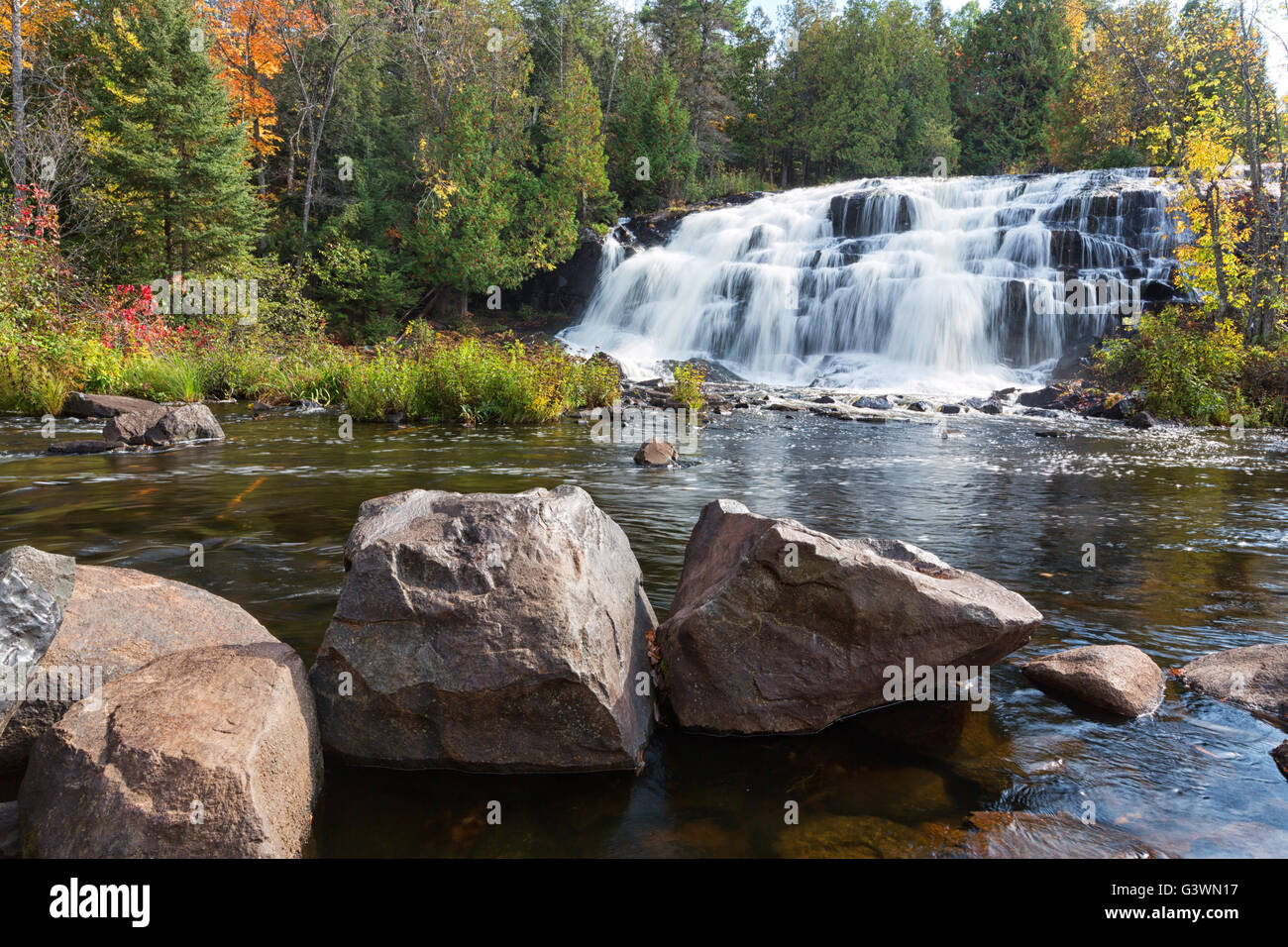 Bond Falls in Paulding Michigan is surrounded by vivid autumn colors. Bond Falls State Park can be found in the Upper Peninsula Stock Photo