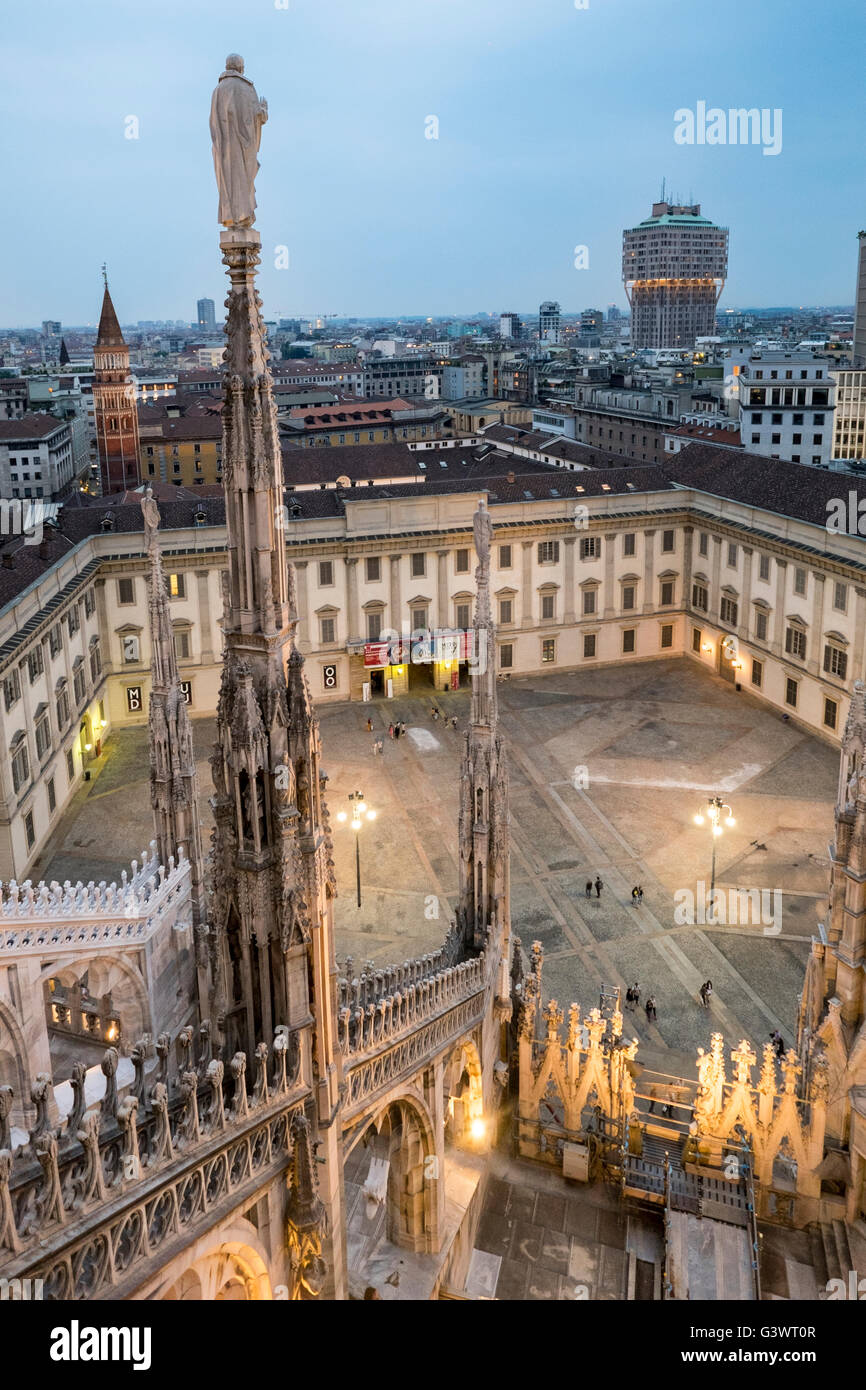 Italy, Milan Cathedral, Metropolitan Cathedral-Basilica of St Mary of the Nativity, Palazzo Reale and the square in front as seen from the roof of the Duomo, among the marble spire; bg.:  Bell Tower of the Church of Saint Gotthard of Hildesheim and The To Stock Photo