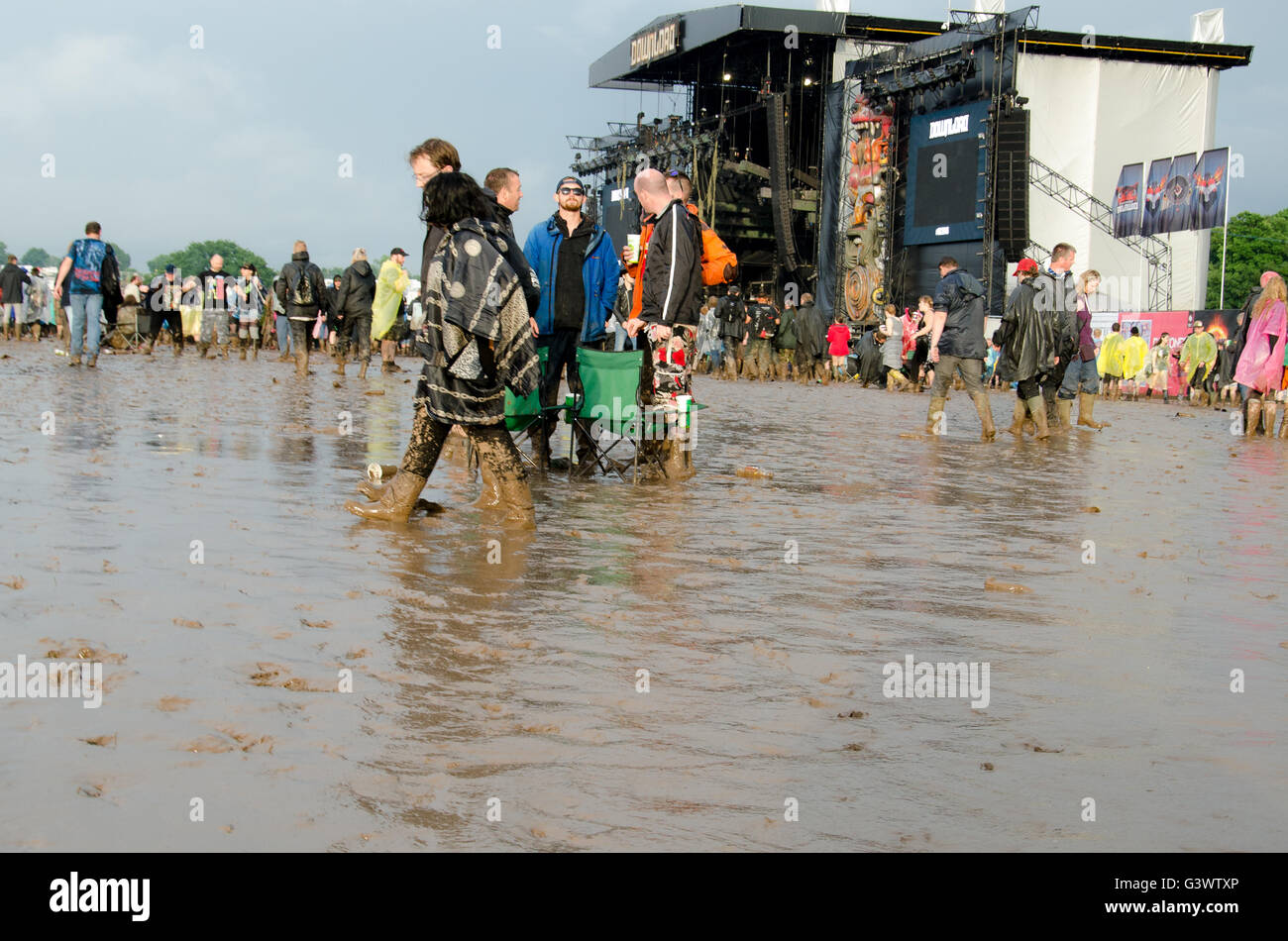 Download music festival main stage set in deep mud with fans with chairs and others dispersing during changeover Stock Photo