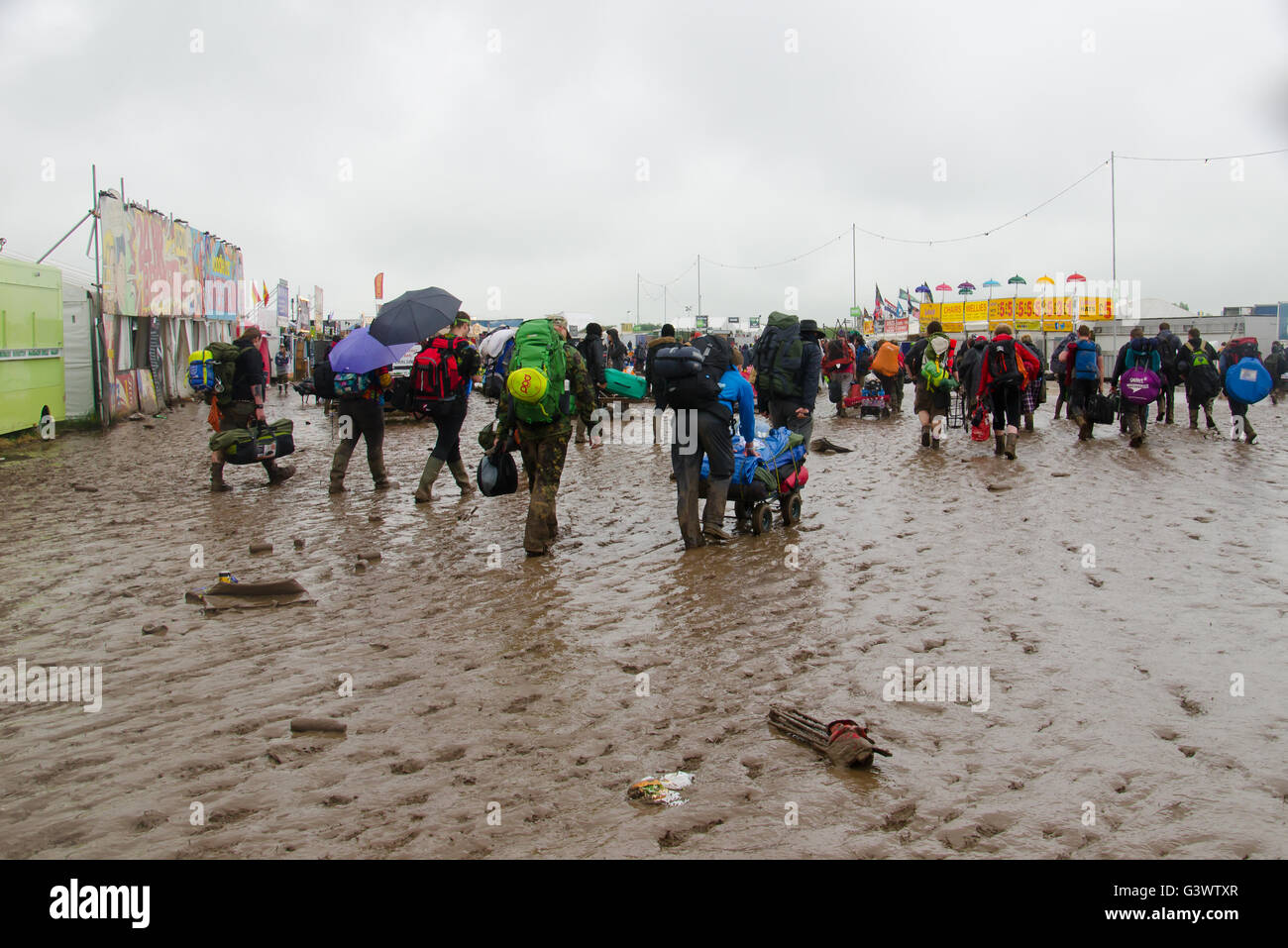 Muddy festival goers leaving download people with camping gear and suitcases trudging in the mud Stock Photo