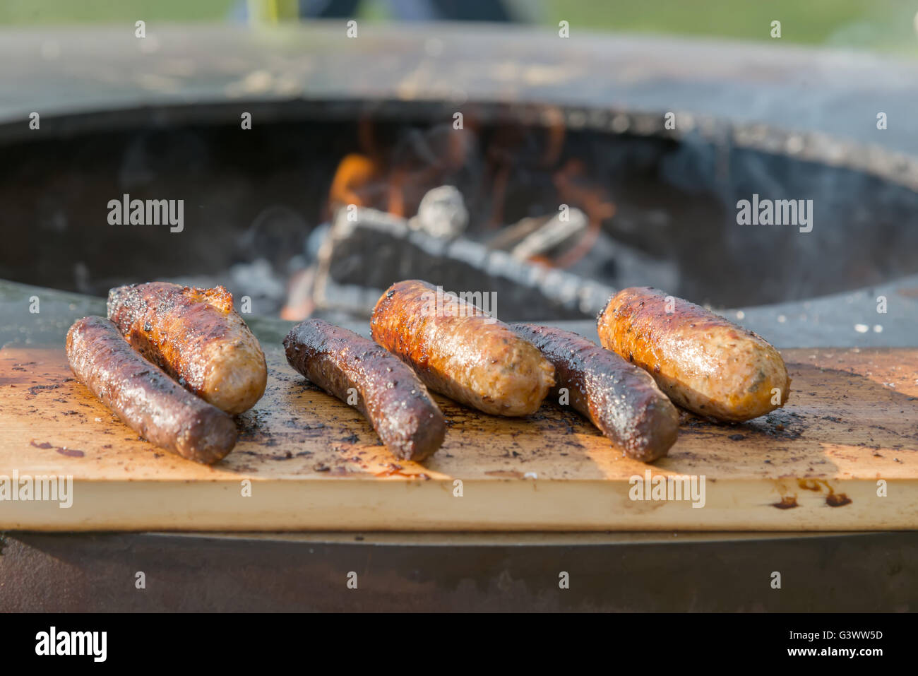 Grilling sausages on cutting board and barbecue grill Stock Photo Alamy