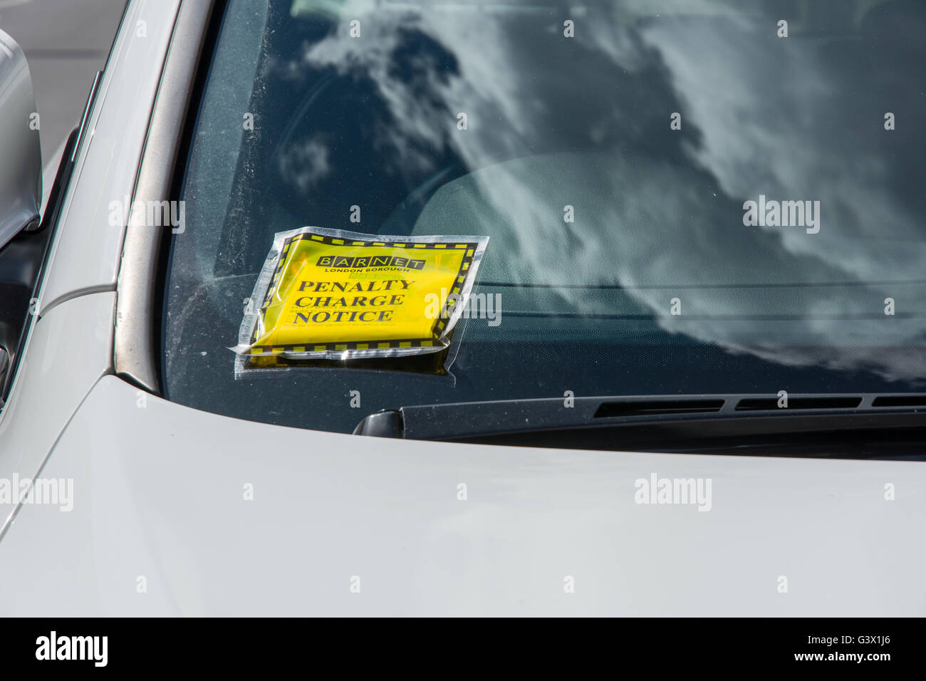 Penalty charge notice (parking fine) attached to windscreen of white car parked in high street London England Stock Photo