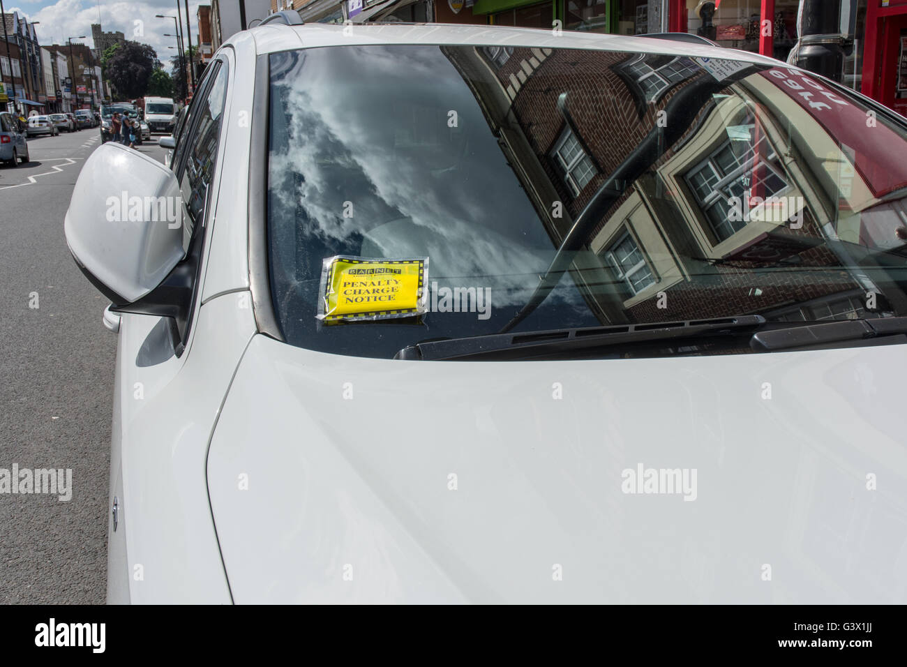 Penalty charge notice (parking fine) attached to windscreen of white car parked in high street London England Stock Photo