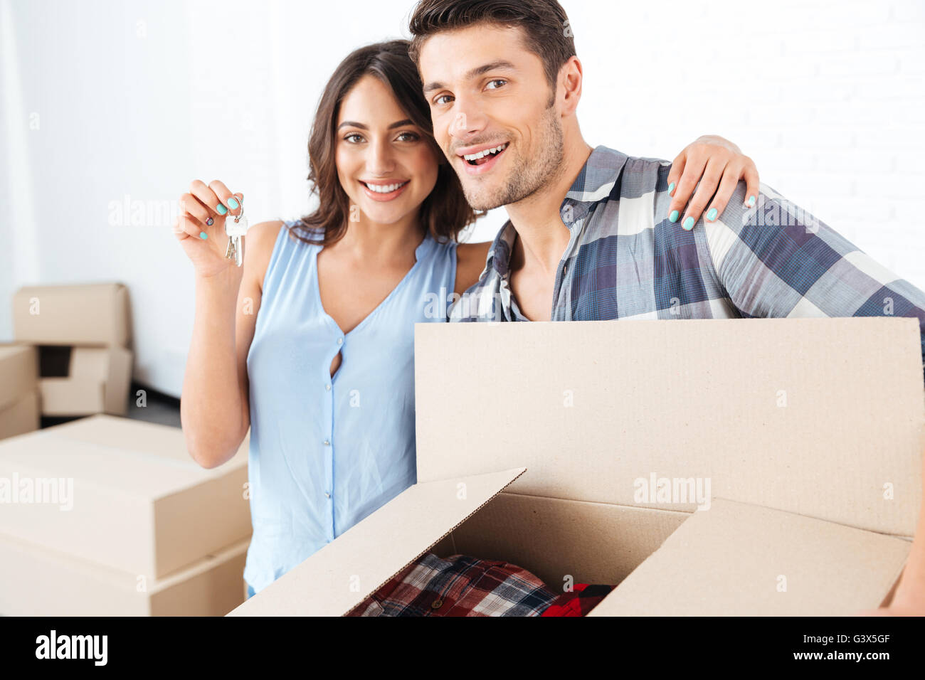 Happy young couple showing keys to new home and hugging Stock Photo - Alamy