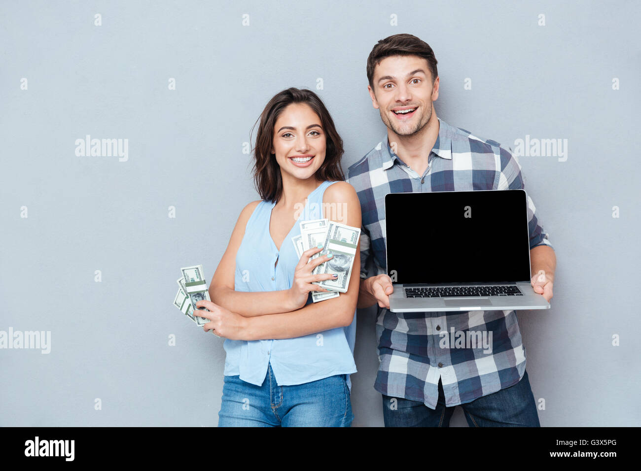 Portrait of happy young couple using laptop with blank screen and ...
