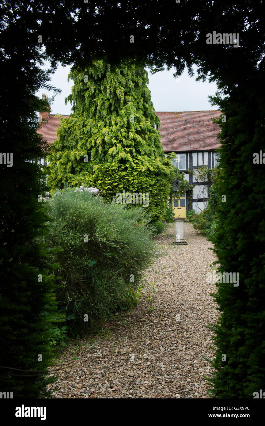 Cottage through a hedge. Ashton Under Hill, Wychavon district, Worcestershire, England Stock Photo