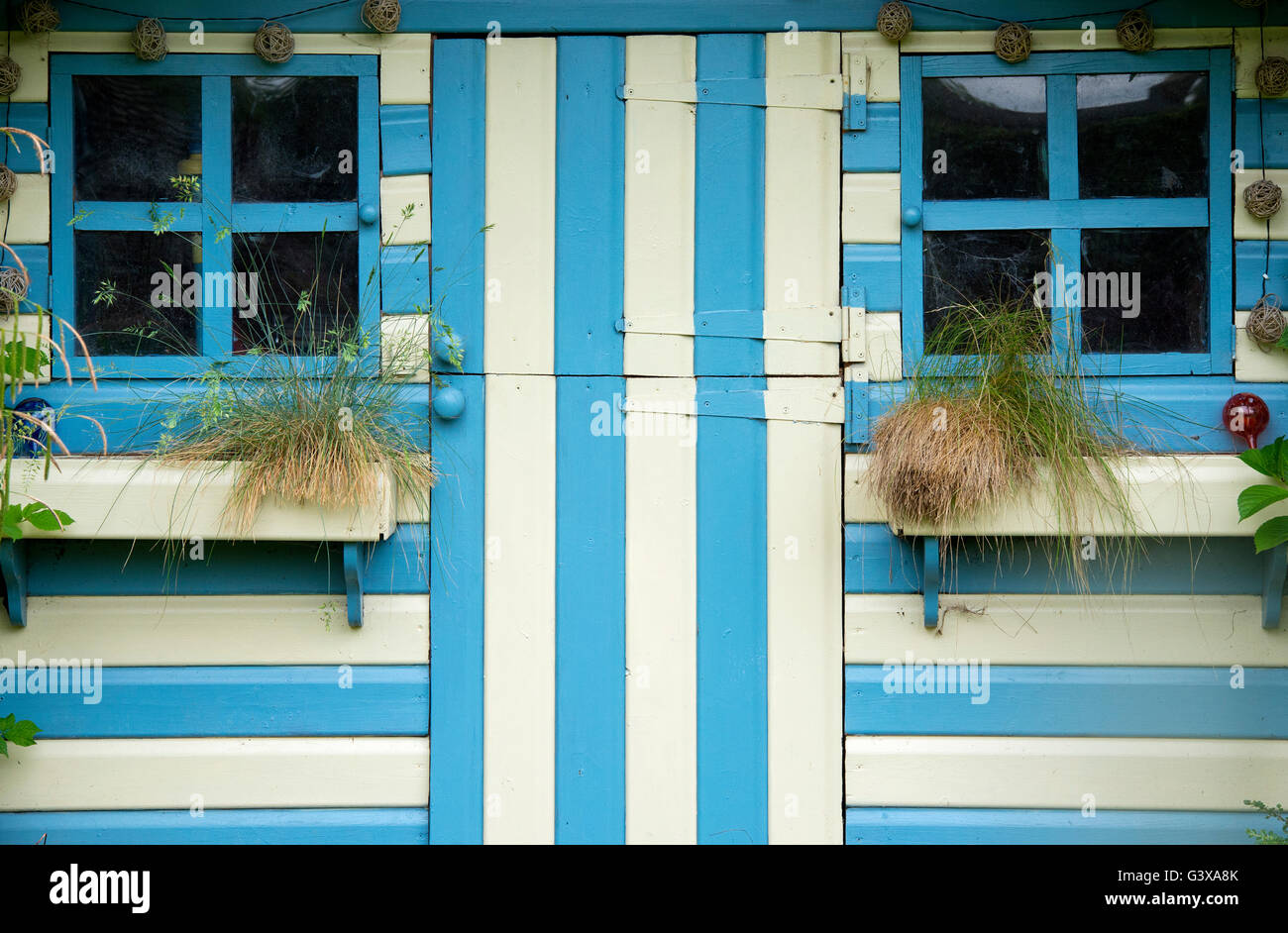 Striped blue and cream painted summer house in a cottage garden. Ashton