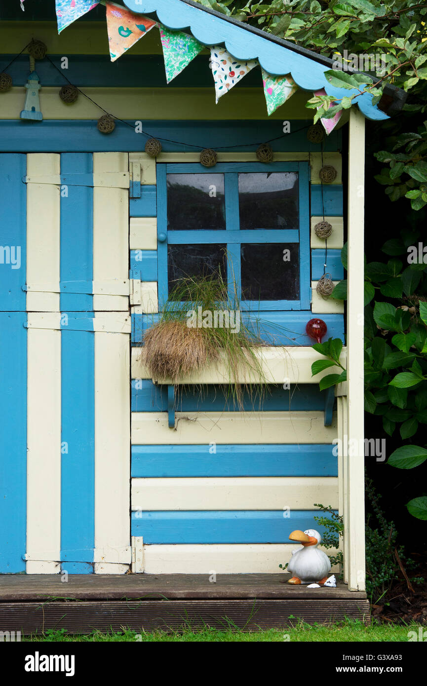 Striped blue and cream painted summer house in a cottage garden. Ashton