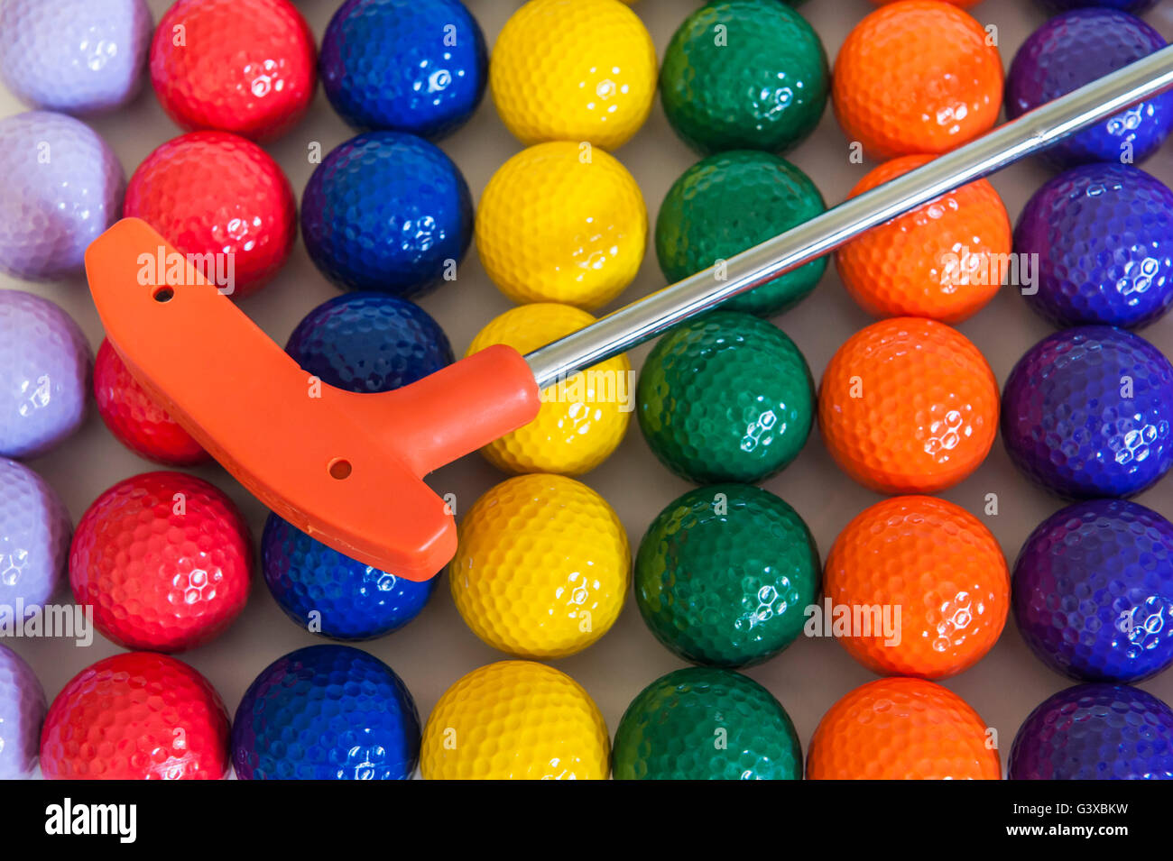 Orange mini golf club with a variety of colorful golf balls Stock Photo