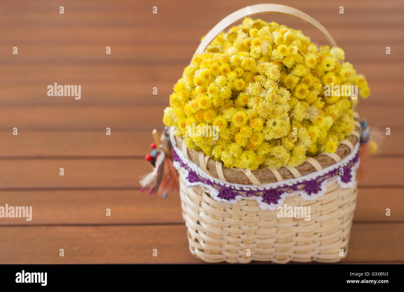 A basket containing helichrysum on wooden table. Stock Photo