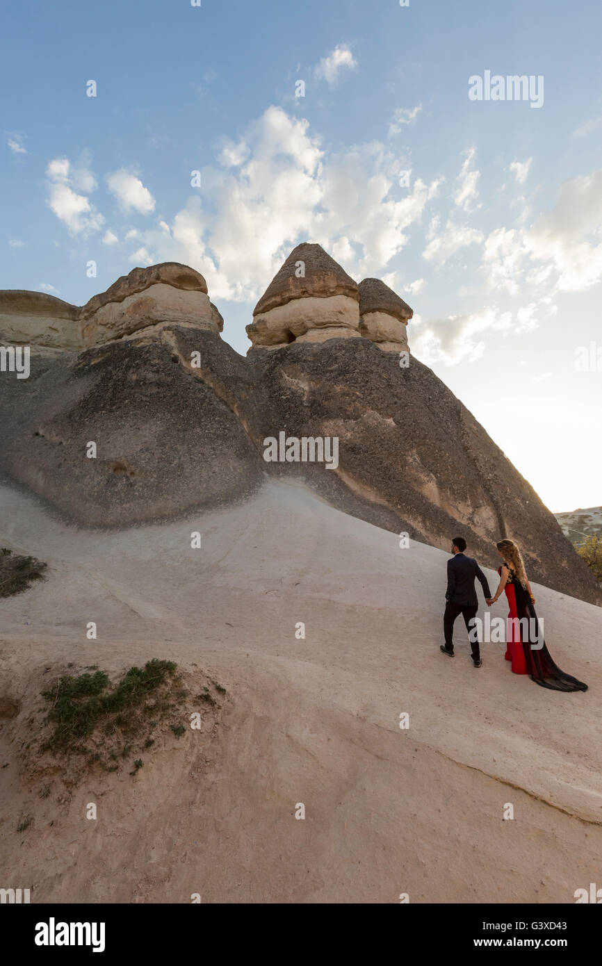 Young couple in nice dresses climbing up the rock formations in Cappadocia, Turkey. Stock Photo