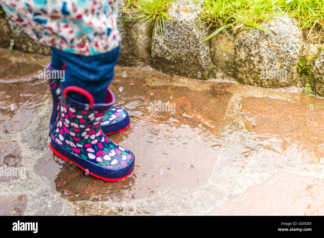 Child wearing rain boots jumping into a puddle Stock Photo - Alamy