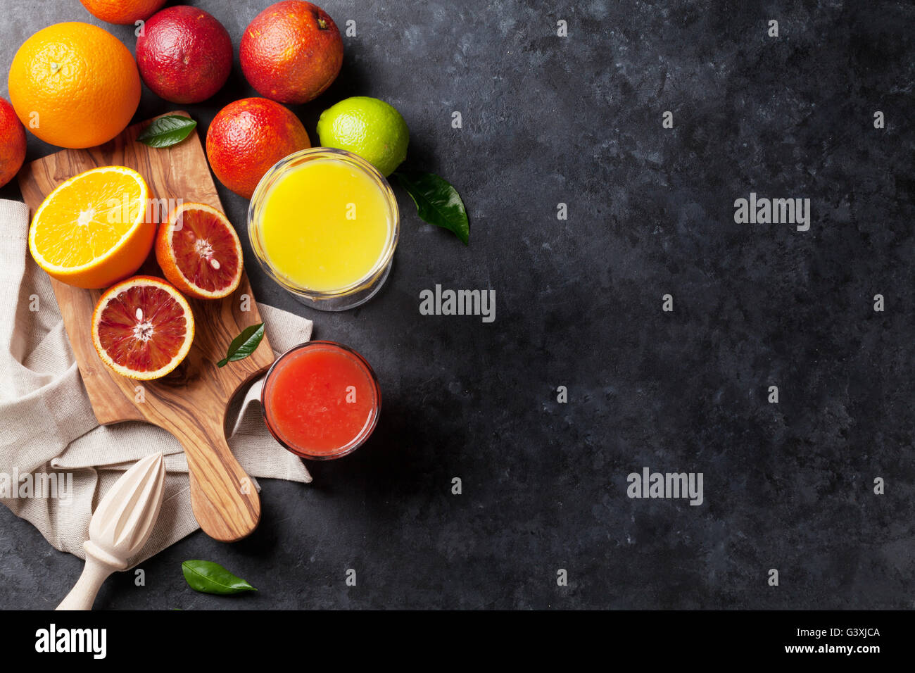 Fresh citruses and juice on dark stone background. Oranges and limes. Top view with copy space Stock Photo