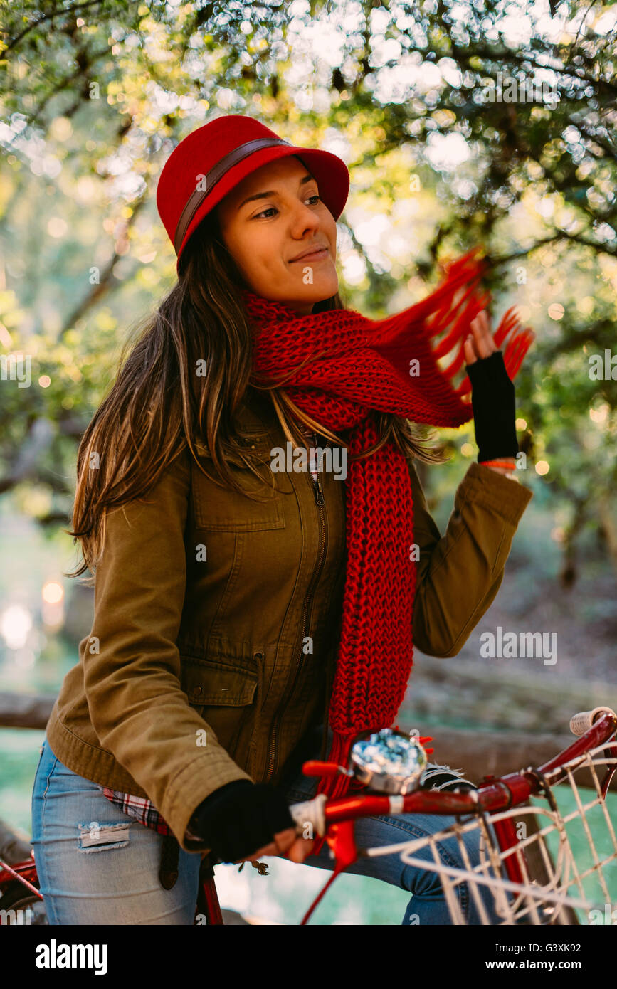 Happy young woman riding bike at the park on sunny autumn day, urban fashion style girl enjoying leisure activity. Stock Photo