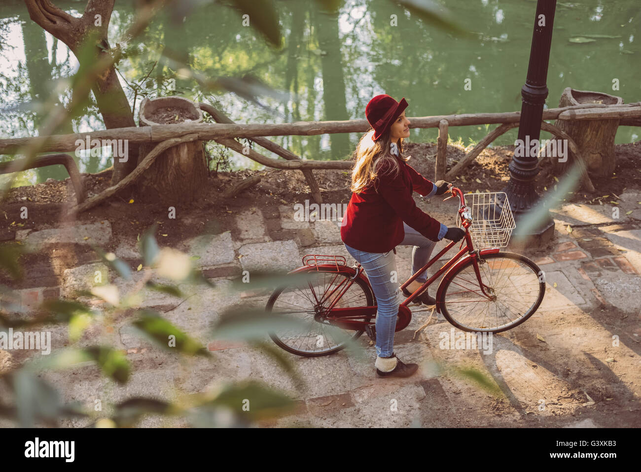 High angle view of happy girl riding bike at park in vintage urban fashion, nature scenery background. Stock Photo
