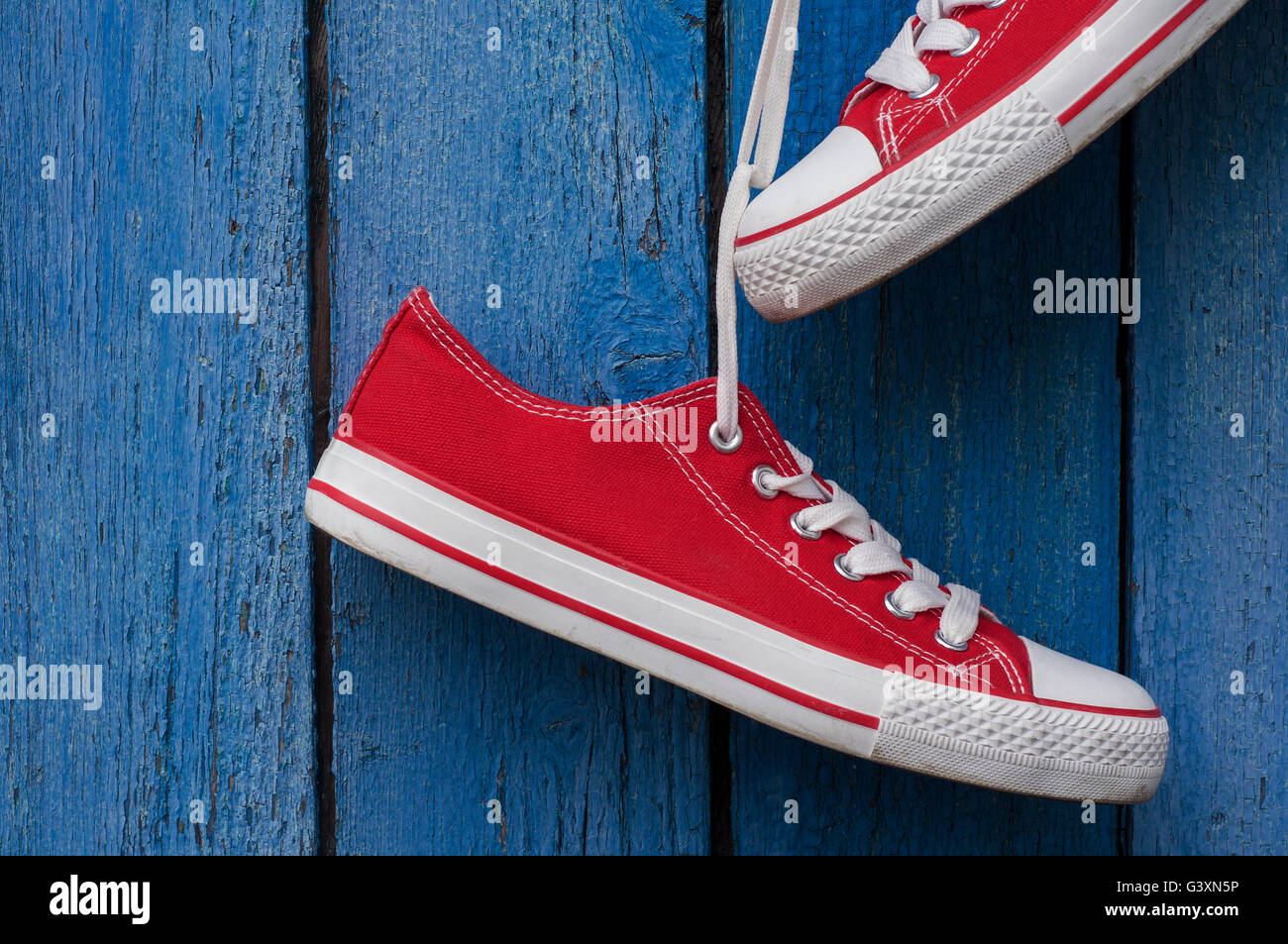 pair of red sneakers on a wooden background old blue Stock Photo - Alamy