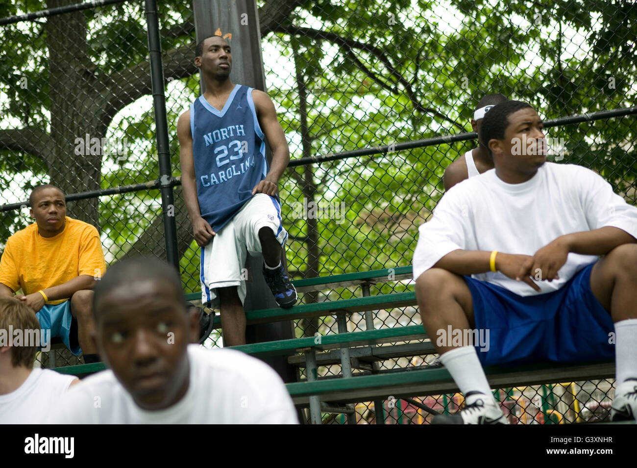Competitors Christophe Bogart (CL), 20, and others watch a game during the tryouts for the Rucker street basketball tournament, Stock Photo